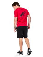 Alpinestars Formulate Csf Tee, T-shirt met korte mouwen, rood, groot zwart geperforeerd Astars-logo op de rug, gedragen met zwarte shorts en sneakers, casual motorsport-geïnspireerde streetwear
