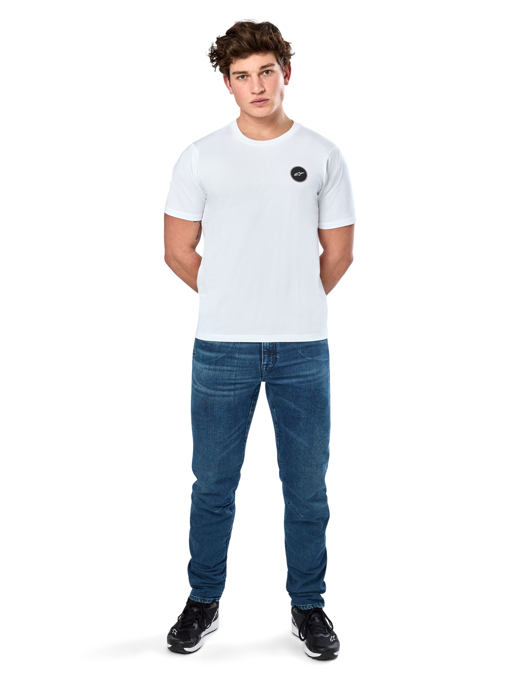 Alpinestars Dot Carbon Csf Tee, T-shirt met korte mouwen, wit, rond Astars-logo met carbon fiber look, casual motorsport streetwear, gedragen door een mannelijk model met blauwe jeans en zwarte sneakers