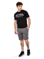 Alpinestars Prevail Csf Tee, T-shirt met korte mouwen, zwart, wit Alpinestars-logo met driekleurige paddock-streep, gedragen met grijze shorts en zwarte sneakers, casual motorsport streetwear