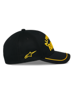 Alpinestars Luminary pet, zwarte snapback cap, zijaanzicht, gebogen klep met gele sutache rand, geel 3D-geborduurd logo en ster aan de zijkant, 100% katoenen keperstof, casual motorsport-geïnspireerde hoofdbedekking