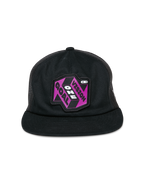 Alpinestars That Way Trucker pet, zwarte trucker cap, voorzien van een paarse en zwarte grafische patch met de tekst "One Vision One Goal", platte klep, gestructureerde kroon en mesh achterpanelen, casual headwear geïnspireerd op de motorsport