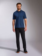 Alpinestars Impetus Sport Polo, poloshirt met korte mouwen, marineblauw, klein zilveren Astars-logo op de borst, sluiting met drie knopen, gedragen door model met zwarte broek en laarzen, casual op de motorsport geïnspireerde sportkleding