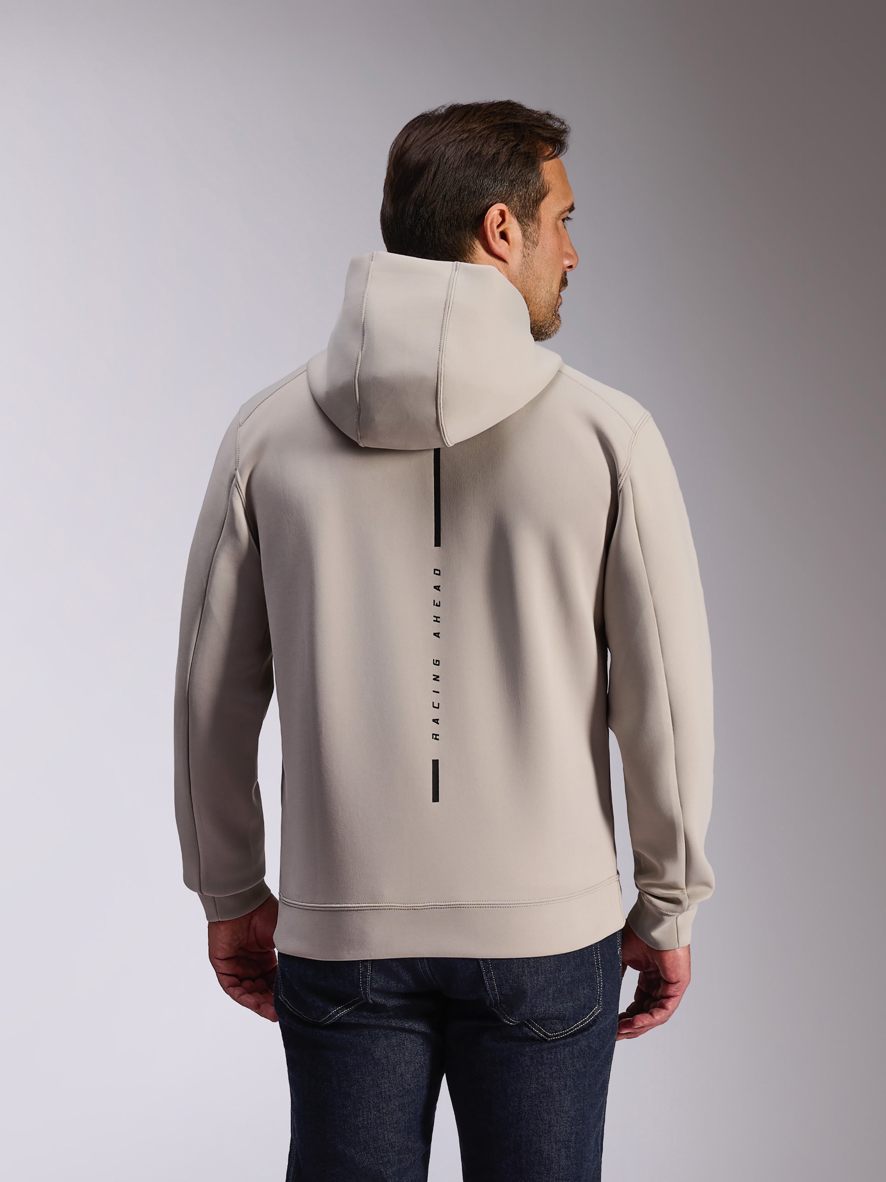 Alpinestars Insight Hoodie in Cement, back view of model wearing a light gray pullover sweatshirt, features a black vertical stripe logo with 'RACING AHEAD' text, casual motorsport-inspired double face fleece hoodie.