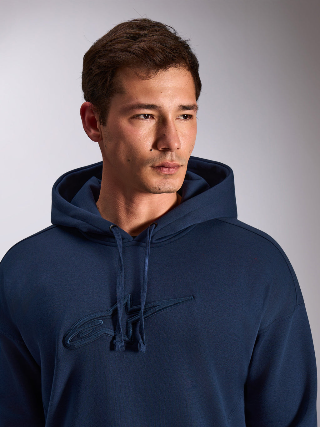 Alpinestars Emergent Oversized Hoodie, navy blue, close-up of model wearing pullover fleece hoodie, featuring tonal 3D embroidered Astars logo on the chest, adjustable drawstring hood, casual motorsport streetwear