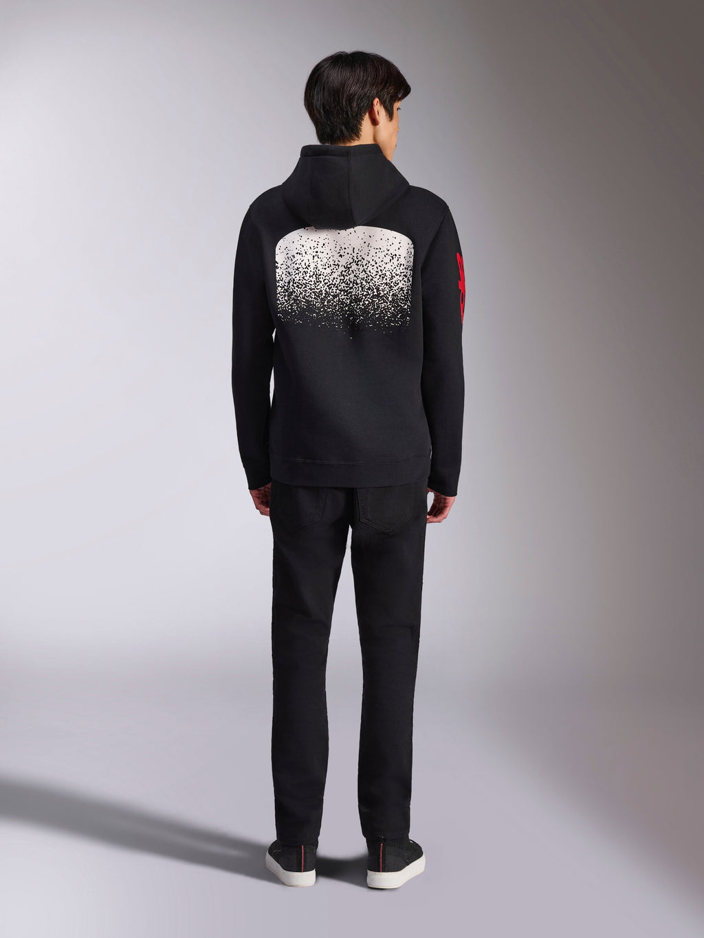 Alpinestars Obsessed Hoodie, casual sportswear, zwart met witte MX-verloopgraphic op de rug, rood woordlogo op de mouw, achteraanzicht, gedragen met een zwarte broek