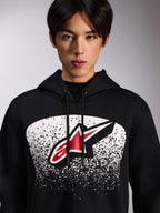 Alpinestars Obsessed Hoodie, zwarte pullover fleece, met een rood en wit Astars-logo binnen een witte gestippelde MX-verloopgrafiek op de borst, gedragen door een model, casual motorsport streetwear met verstelbare capuchon met trekkoord