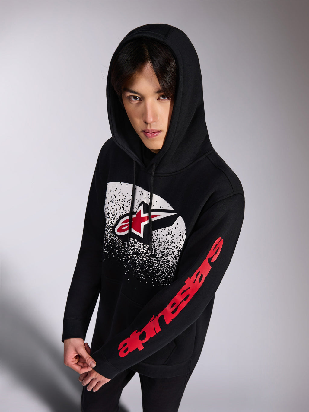 Alpinestars Obsessed Hoodie, zwarte pullover fleece hoodie, rood en wit Astars-logo op de voorzijde met wit distressed MX-verloop, rood Alpinestars-woordmerk op de mouw, capuchon met trekkoord, casual motorsport-geïnspireerde streetwear