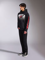 Alpinestars Obsessed Hoodie, zwarte pullover fleece met een grote wit gespikkelde graphic op de borst, rood Astars-logo en rode branding op de mouwen, gedragen door een model met zwarte broek en sneakers, casual motorsport streetwear