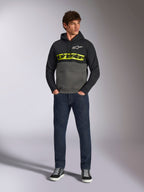 Alpinestars Parallel Hoodie, color-blocked pullover, Black and Gunmetal gray, bright yellow Alpinestars word logo and white star logo on chest, worn by a male model with dark blue jeans and black sneakers, casual motorsport streetwear