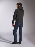 Alpinestars Cypher Hoodie, zwarte casual hoodie met rits, achteraanzicht met hoge capuchon en wit Alpinestars-logo op de onderrug, gedragen met donkerblauwe jeans en zwarte sneakers, modern motorsport-geïnspireerd ontwerp