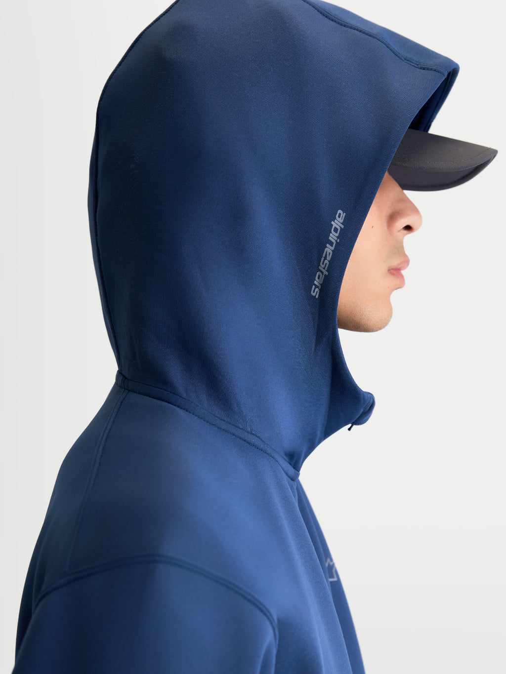 Alpinestars Cypher hoodie, motorsport-geïnspireerde sportswear, blauw, unisex fleece hoodie met ritssluiting, capuchon met hoge hals en meshvoering voorzien van Alpinestars-woordmerk aan de zijkant, zijprofiel op model.
