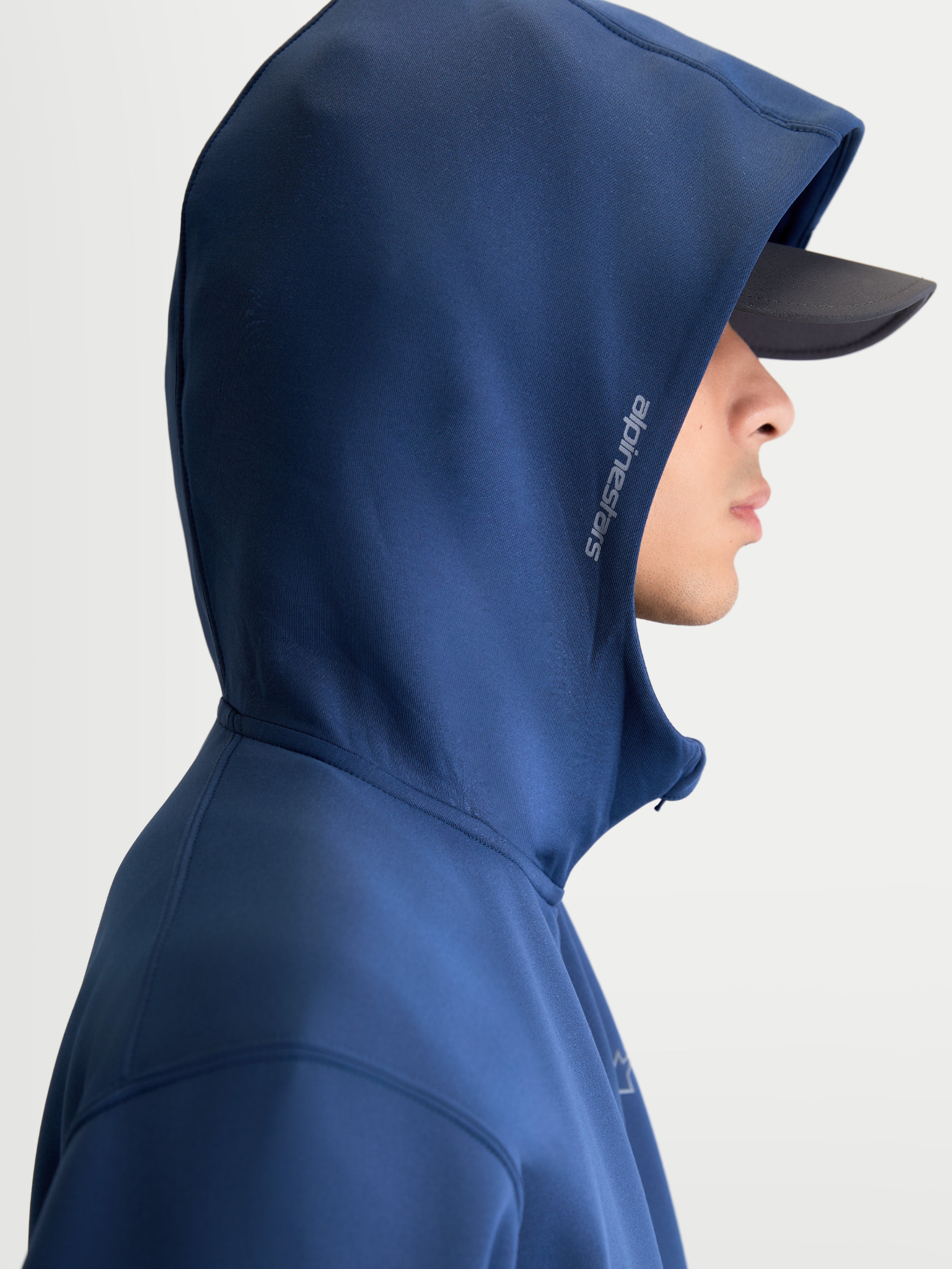 Alpinestars Cypher hoodie, motorsport-geïnspireerde sportswear, blauw, unisex fleece hoodie met ritssluiting, capuchon met hoge hals en meshvoering voorzien van Alpinestars-woordmerk aan de zijkant, zijprofiel op model.