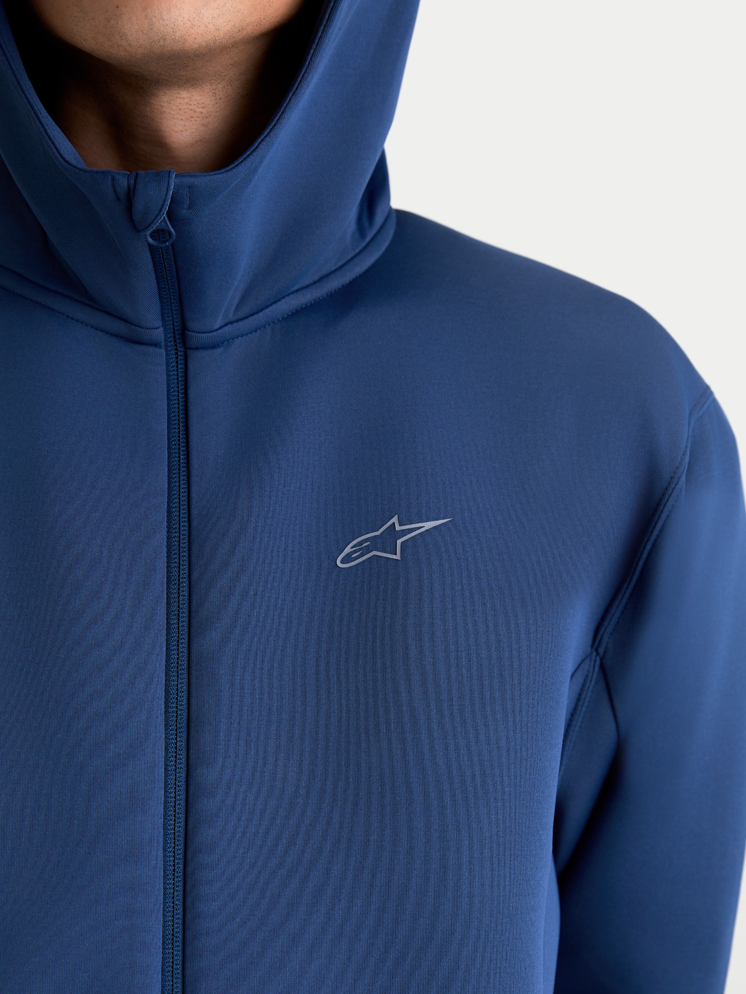 Alpinestars Cypher hoodie, sportieve hoodie voor heren en dames, blauw, technische tri-blend dubbelzijdige fleece stof, capuchon met hoge hals, Astars-logodetail, close-up op model.