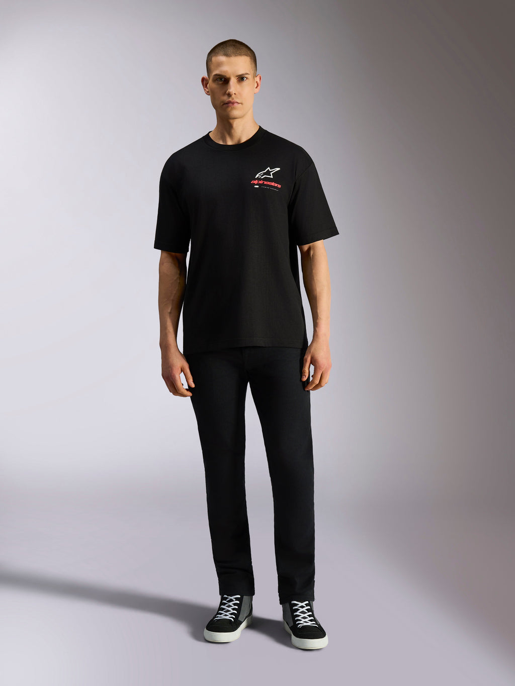 Alpinestars Overhang Oversized CSF Tee, Short Sleeve T-Shirt, Black, White Astars Logo with Red Text, worn by a model with black pants and sneakers, casual motorsport streetwear