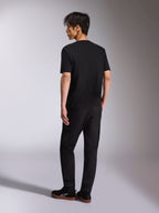 Alpinestars Noka CSF Tee, T-shirt met korte mouwen, zwart, achteraanzicht getoond op model, gecombineerd met zwarte broek en casual sneakers, minimalistische motorsport streetwear