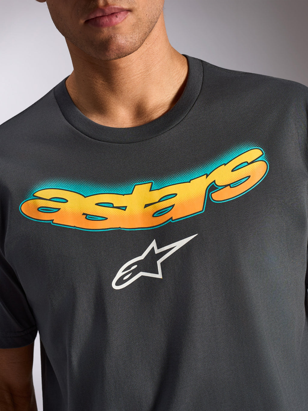 Alpinestars Ellipsoid CSF Tee, T-shirt met korte mouwen, antracietgrijs, gebogen 'astars' woordmerk met geel en oranje kleurverloop en teal stippenpatroon, wit Alpinestars sterlogo, vrijetijdskleding geïnspireerd op de motorsport
