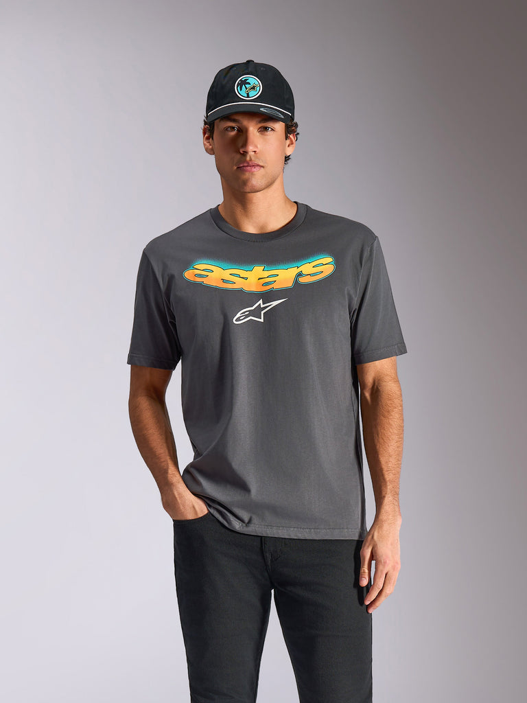 Alpinestars Ellipsoid CSF Tee, T-shirt met korte mouwen, antracietgrijs, gebogen 'astars' tekst met oranje en blauw kleurverloop en een wit logo, gedragen door een model met een zwarte pet en broek, casual motorsport streetwear