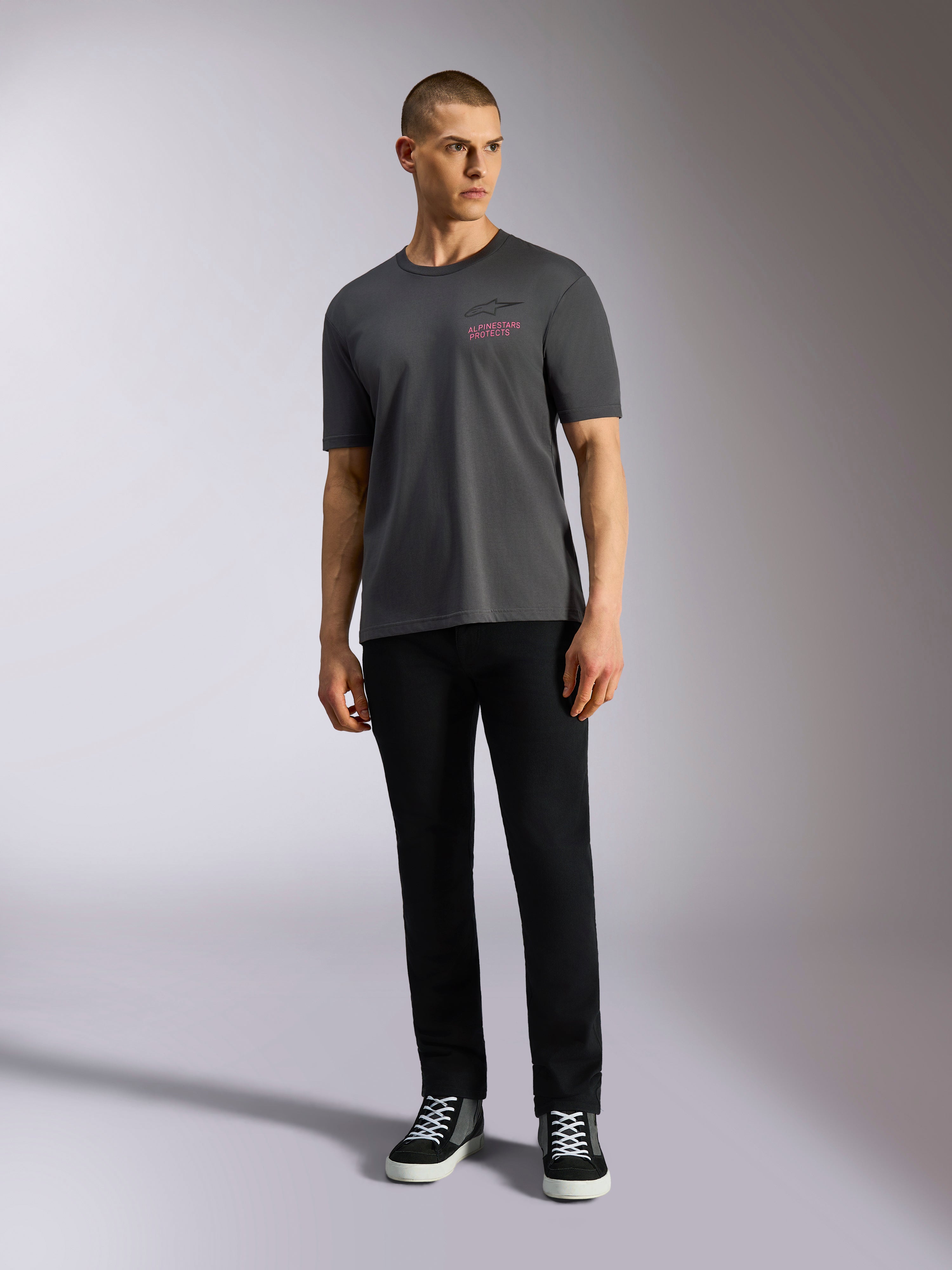 Alpinestars Pop Helmet CSF Tee, Short Sleeve T-Shirt, Charcoal Gray, featuring a pink Alpinestars logo on the chest, worn by a male model with black pants and sneakers, Casual Motorsport Streetwear