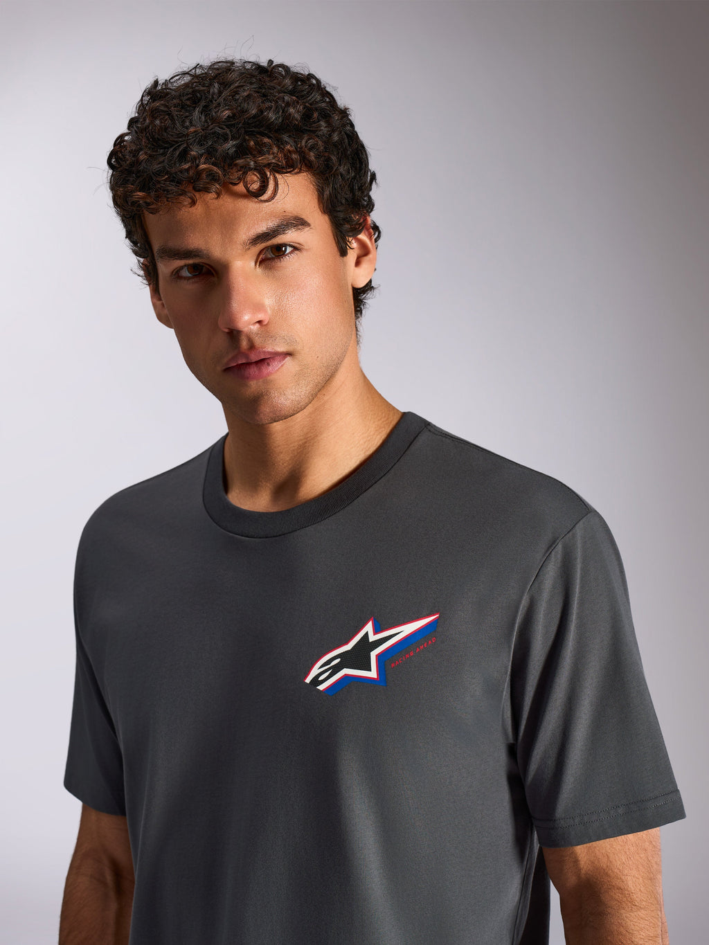 Alpinestars Angler CSF Tee, T-shirt met korte mouwen, antracietgrijs, gedragen door een mannelijk model, voorzien van een meerkleurig Astars-logo op de borst, casual motorsport streetwear