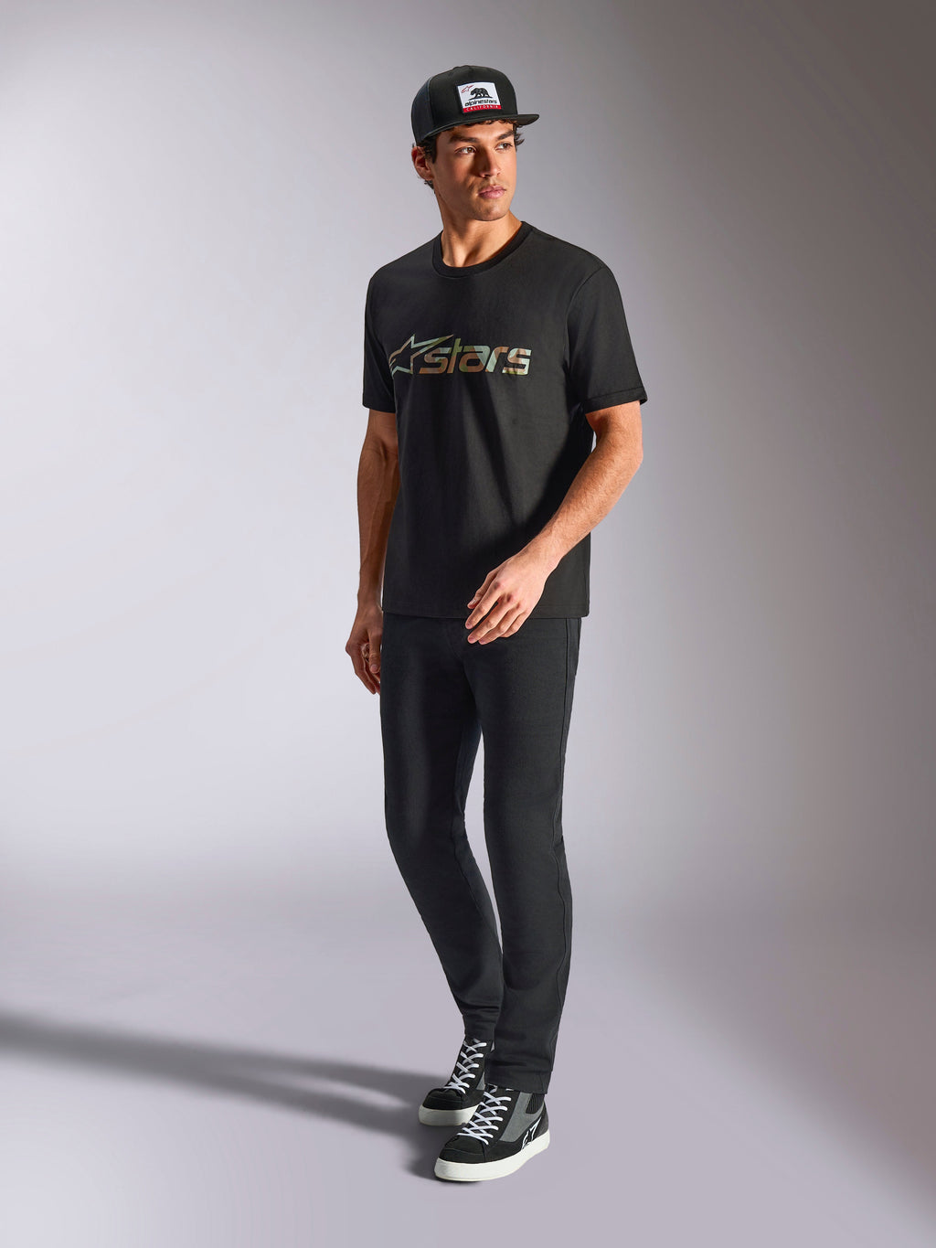 Alpinestars Verdure Camo CSF Tee, Short Sleeve T-Shirt, Black, featuring a Camo Fill Astars Logo on the chest, worn by a model with a black cap and pants, casual motorsport streetwear