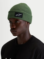 Alpinestars Unload Rib Cuff muts, erwtgroene casual wintermuts gedragen door een model, met een gebreide jerseysteek en een zwart-witte SAstars geweven patch aan de voorkant