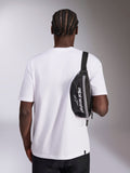 Alpinestars Only Linear heuptas, zwart met wit Alpinestars-logo, gedragen als crossbodytas over een wit T-shirt, casual motorsport-geïnspireerd streetwear-accessoire