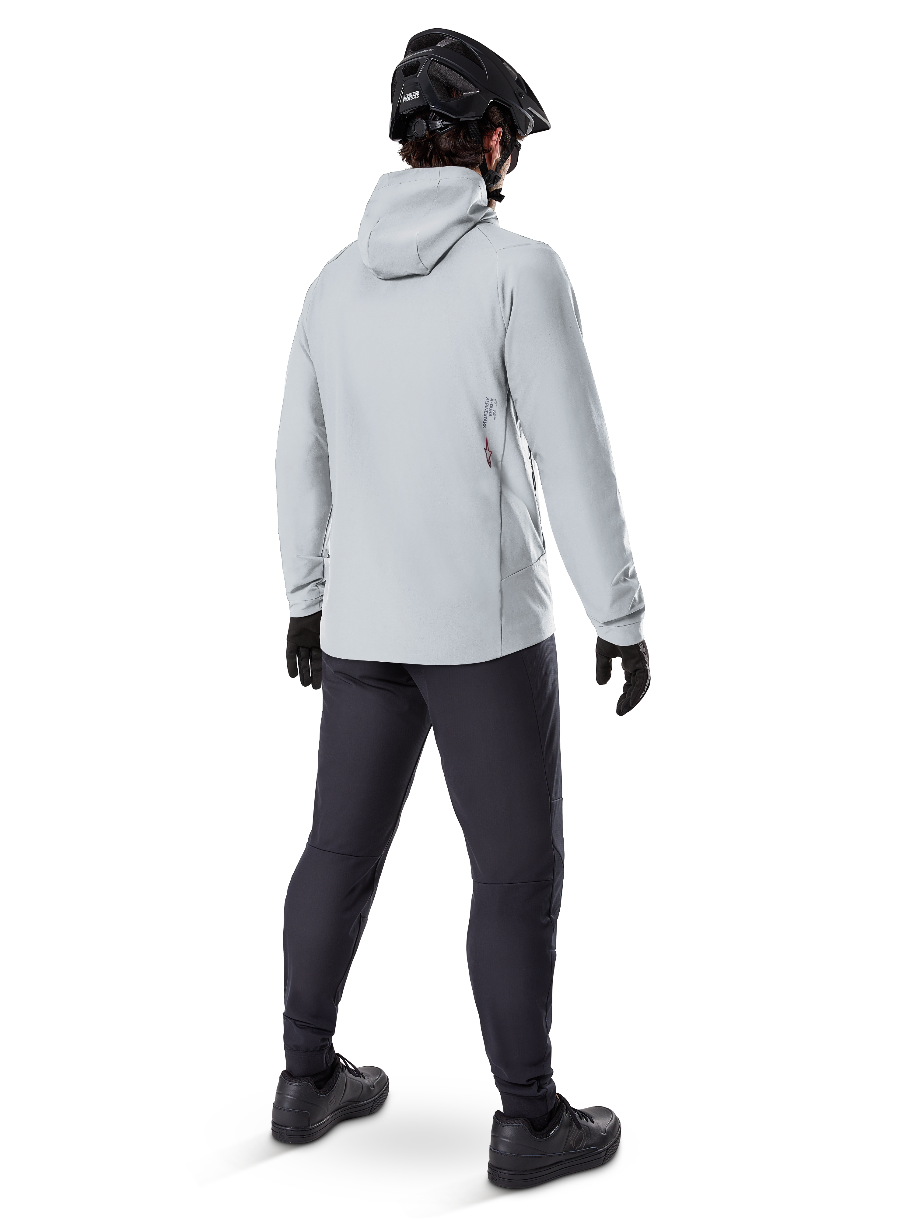 Alpinestars A-Dura Thermal Jacket in Titanium, back view of male cyclist wearing light gray hooded thermal jacket, paired with black MTB helmet, black gloves, and dark gray pants, functional mountain bike riding gear.