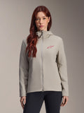 Alpinestars Stella A-Dura Thermal Jacket voor dames, titaniumgrijs, ontwerp met rits en capuchon, rood sterlogo op de borst, gecombineerd met een zwarte broek, lifestyle studioportret