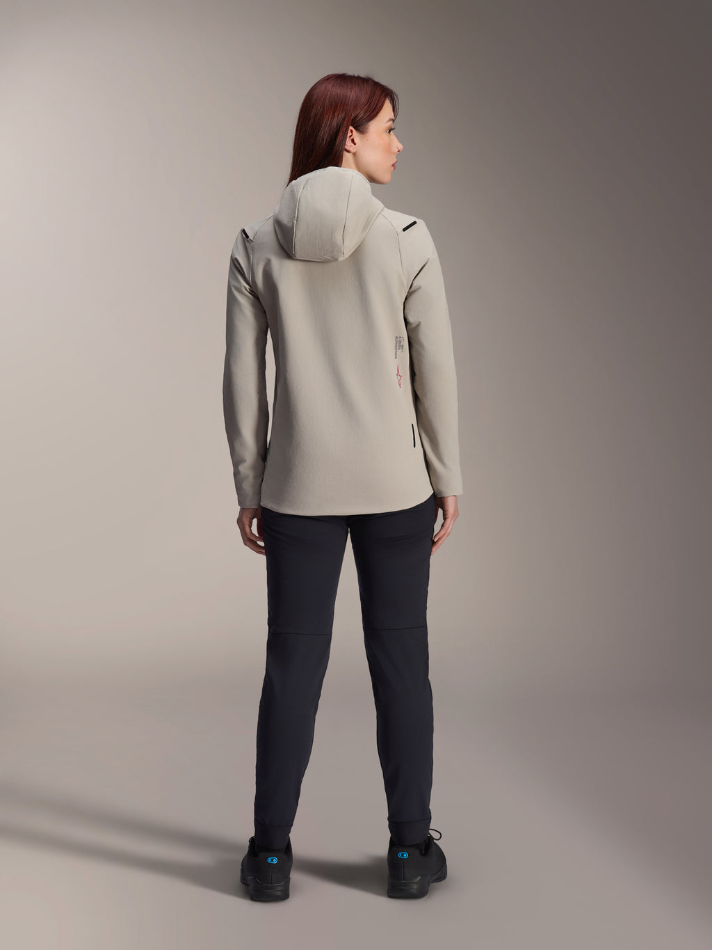 Alpinestars Stella A-Dura Thermal Jacket voor dames, Titanium grijs, achteraanzicht gedragen met een zwarte broek, voorzien van een met fleece gevoerde geïsoleerde capuchon en een klein rood logo, functionele en stijlvolle mountainbikejas voor ritten in koud weer.