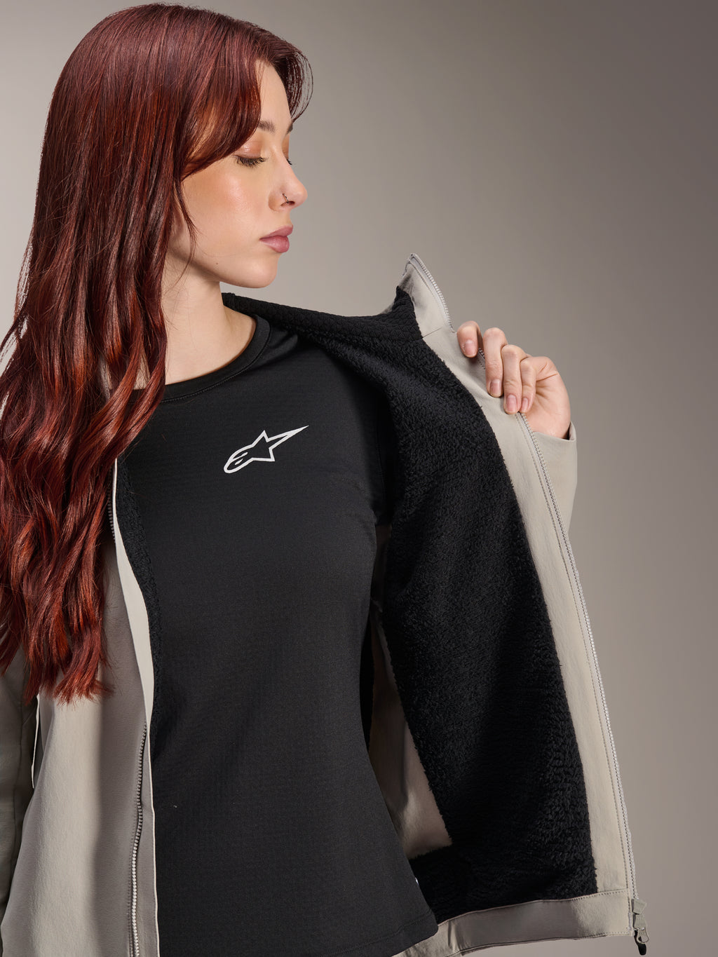 Alpinestars Stella A-Dura Thermal Jacket in Titanium, vrouw draagt de jas en toont de zwarte getextureerde fleece voering, gedragen over een zwart t-shirt met wit sterlogo, lichtgewicht mountainbikejas voor koude omstandigheden