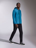 Alpinestars Speeder Chromium Windbreak Jacket, Blue hooded windbreaker worn by a male model, features a black front zipper and chest logo, paired with black pants and high-top sneakers, casual motorsport-inspired sportswear