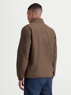 Alpinestars Overhaul Racer jas, lichtgewicht sportswear jas voor heren, bruin, polyester materiaal, achteraanzicht met focus op strak silhouet en hoge kraag met verborgen capuchon.