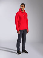 Alpinestars Frontal Hoodie, rood, mannelijk model in pullover fleece hoodie met wit A-star logo op de borst, kangoeroezak en capuchon met trekkoord, gecombineerd met donkere denim jeans, casual op motorsport geïnspireerde streetwear