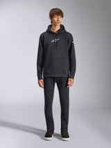 Alpinestars Frontal Hoodie, zwarte pullover fleece hoodie, wit Alpinestars-logo op de borst en mouw, kangoeroezak, capuchon met trekkoord, gedragen met een zwarte broek, casual motorsport-geïnspireerd ontwerp