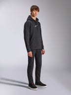 Alpinestars Frontal Hoodie, zwart, pullover fleece hoodie met wit HD-logo op de borst en woordmerklogo's op de mouwen, kangoeroezak, gecombineerd met een zwarte broek en sneakers, casual motorsport-geïnspireerde streetwear