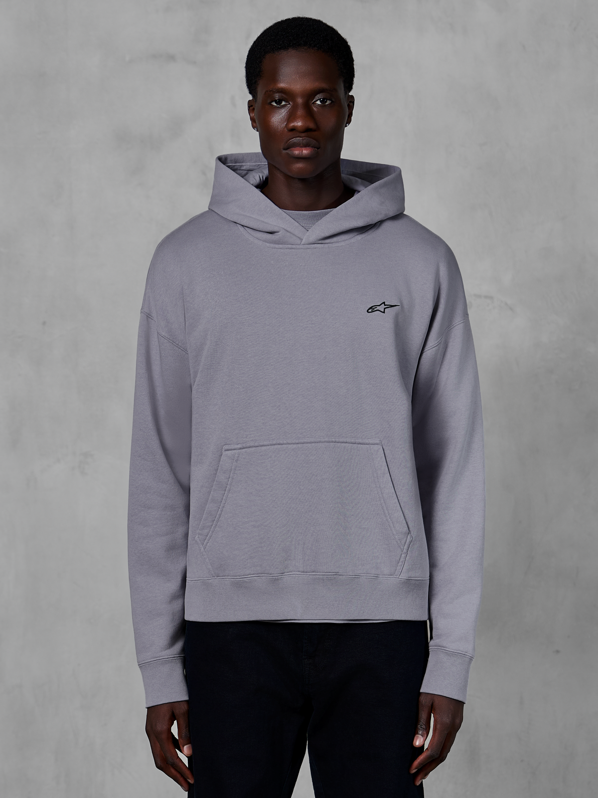 Alpinestars Essentials Ageless Hoodie, zilveren pullover hoodie, casual streetwear, met een klein zwart Astars-logo op de borst, kangoeroezak aan de voorzijde, capuchon met crossover-hals en een zachte stone wash afwerking.