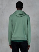 Alpinestars Essentials Ageless Hoodie, casual sportkleding, Cactusgroen, achteraanzicht op model, garment stone wash afwerking, gecombineerd met zwarte broek, minimalistisch lifestyle-ontwerp