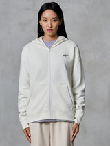 Alpinestars Essentials Ageless Zip Hoodie, Off White, fleece sweatshirt met ritssluiting gedragen door een model, voorzien van een klein zwart Astars-logo op de borst, relaxte pasvorm, casual motorsport-geïnspireerde lifestylekleding