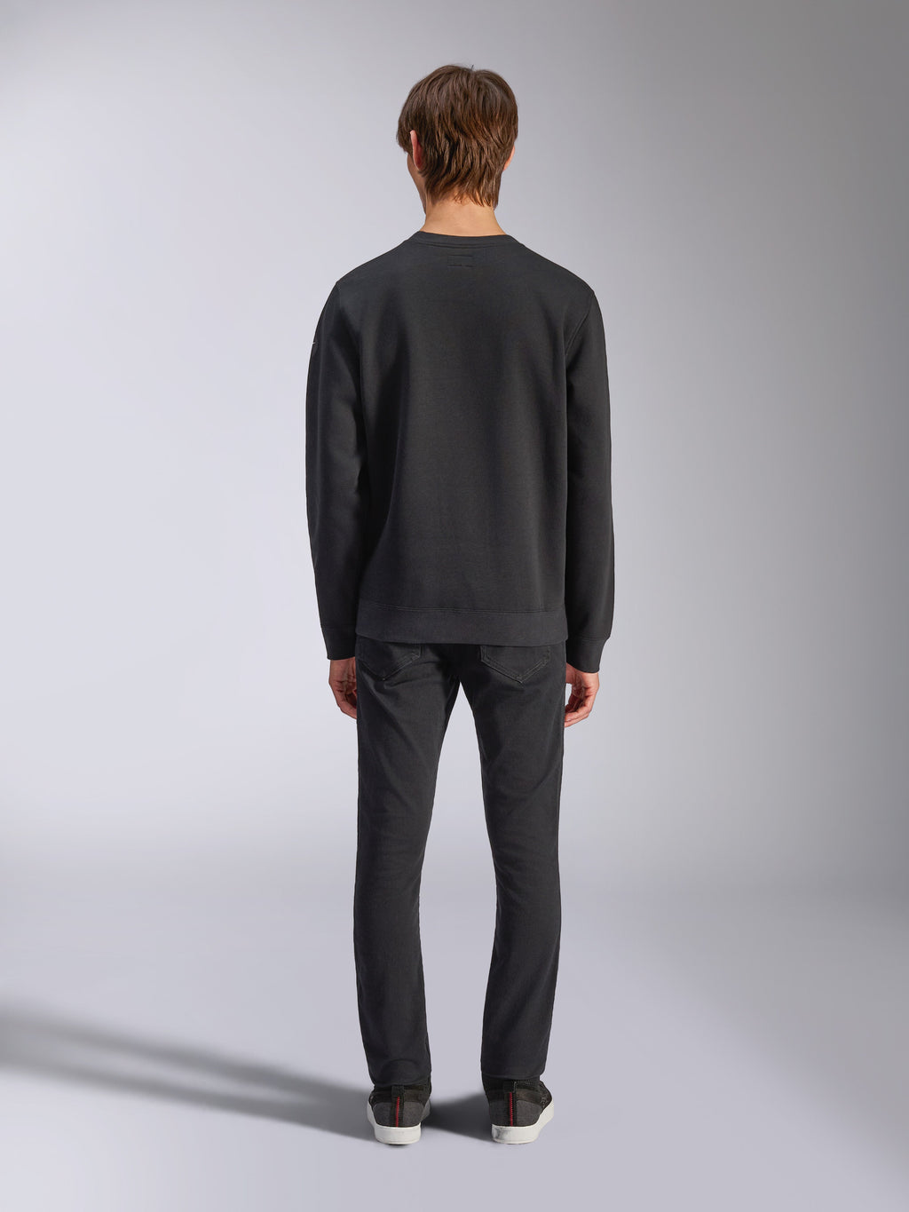 Alpinestars Bettern Crew, zwarte sweatshirt met ronde hals, achteraanzicht op model, geribbelde kraag en zoom, casual motorsport-geïnspireerde streetwear