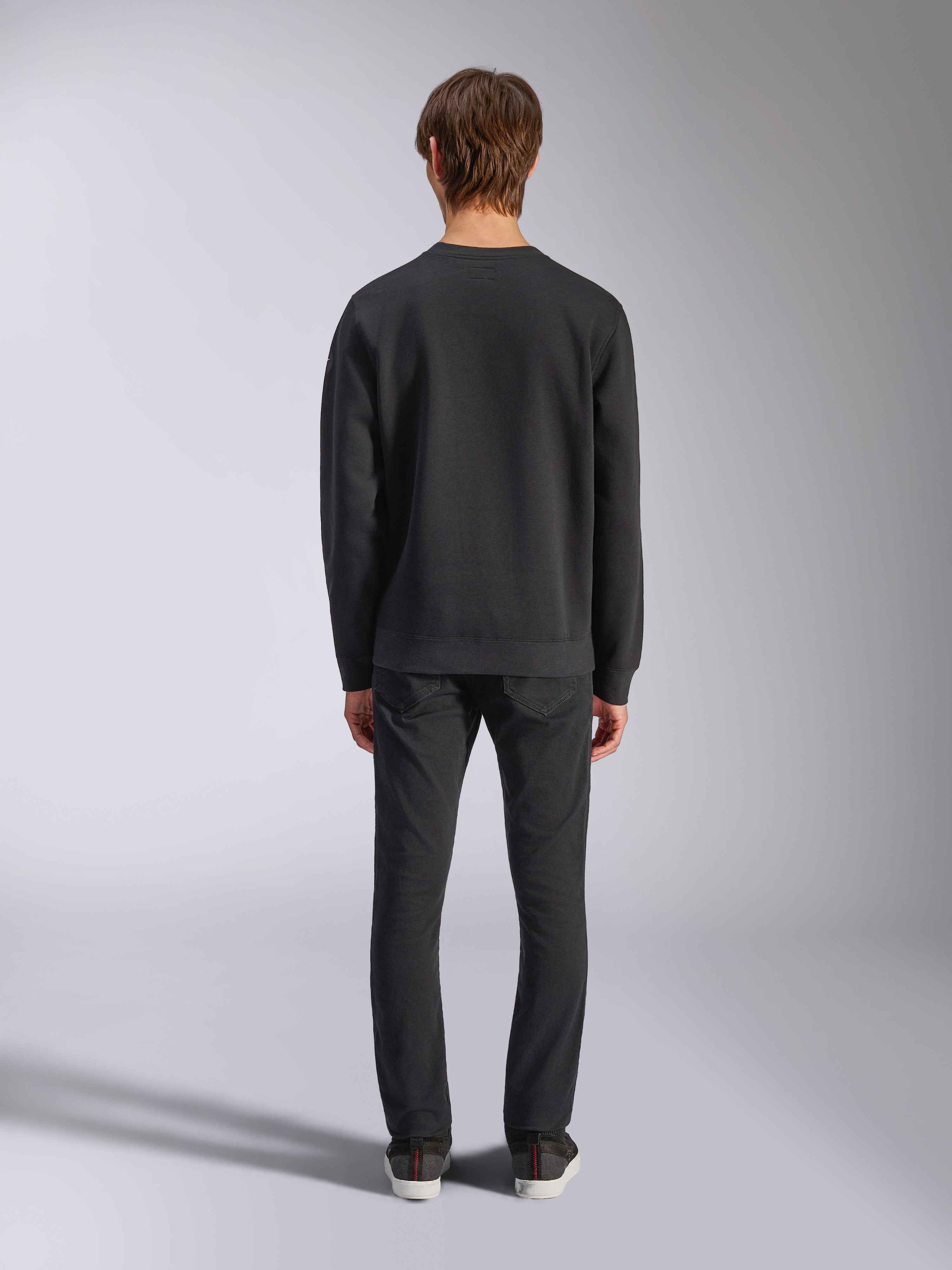 Alpinestars Bettern Crew, zwarte sweatshirt met ronde hals, achteraanzicht op model, geribbelde kraag en zoom, casual motorsport-geïnspireerde streetwear