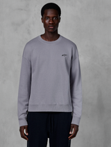 Alpinestars Essentials Ageless Crew, zilverkleurige sweatshirt met ronde hals gedragen door een model, voorzien van een klein zwart sterlogo op de borst, ontspannen pasvorm met geribbelde manchetten en zoom, casual motorsport streetwear