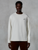 Alpinestars Essentials Ageless LS Tee, T-shirt met lange mouwen, gebroken wit, klein zwart sterlogo op de borst, casual streetwear, ontspannen pasvorm, gedragen door een model