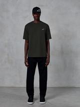 Alpinestars Essentials Ageless SS Tee, T-shirt met korte mouwen, Off Black, met een klein wit Alpinestars-logo op de borst, gedragen door een model met een zwarte pet en broek voor een strakke lifestyle-look