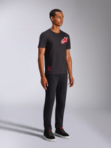 Alpinestars Shaded CSF Tee, T-shirt met korte mouwen, zwart, rood en wit schuin verlopend folieprint Astars-logo, casual motorsport streetwear, volledige opname van een model met zwarte broek en sneakers