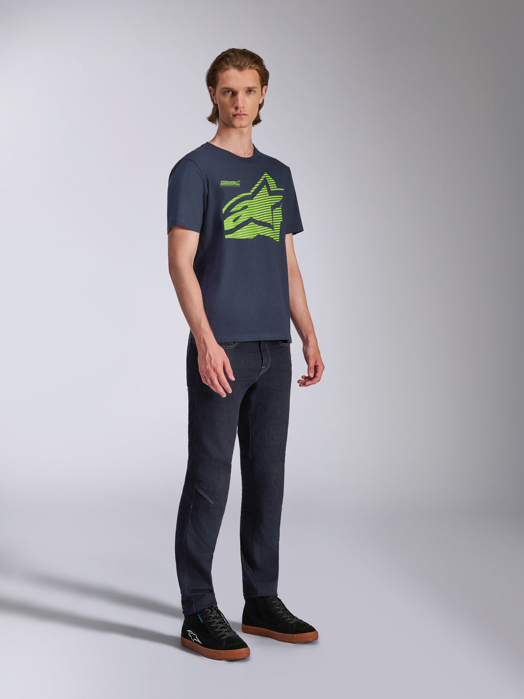 Alpinestars Fasting CSF Tee, T-shirt met korte mouwen, donkerblauw, limoengroen geometrisch Astars-logo, gedragen met donkere jeans en zwarte sneakers, casual motorsport streetwear