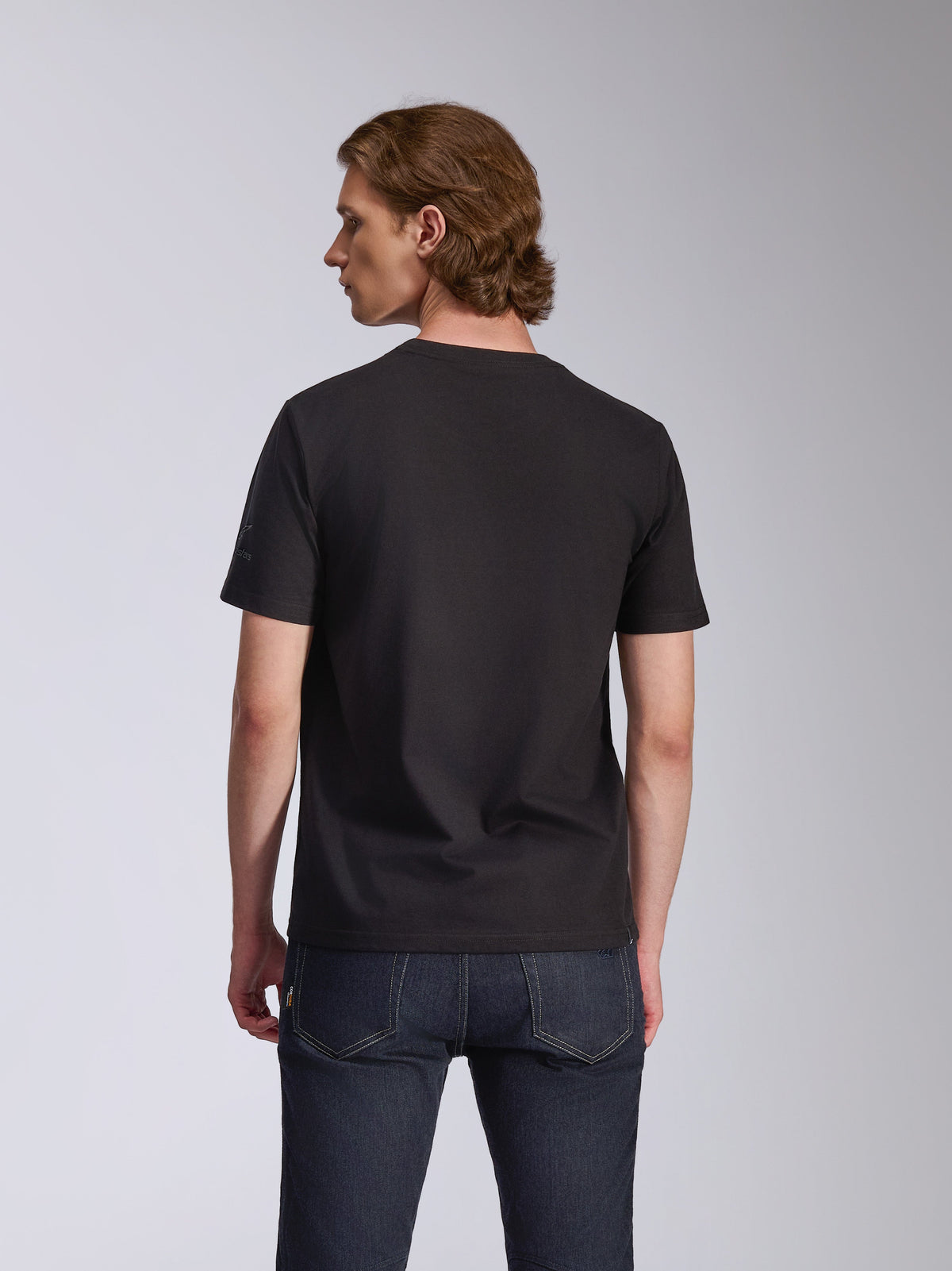 Alpinestars Global CSF Tee, T-shirt met korte mouwen, zwart, achteraanzicht gedragen door een model, gecombineerd met een donkerblauwe jeans, casual motorsport streetwear
