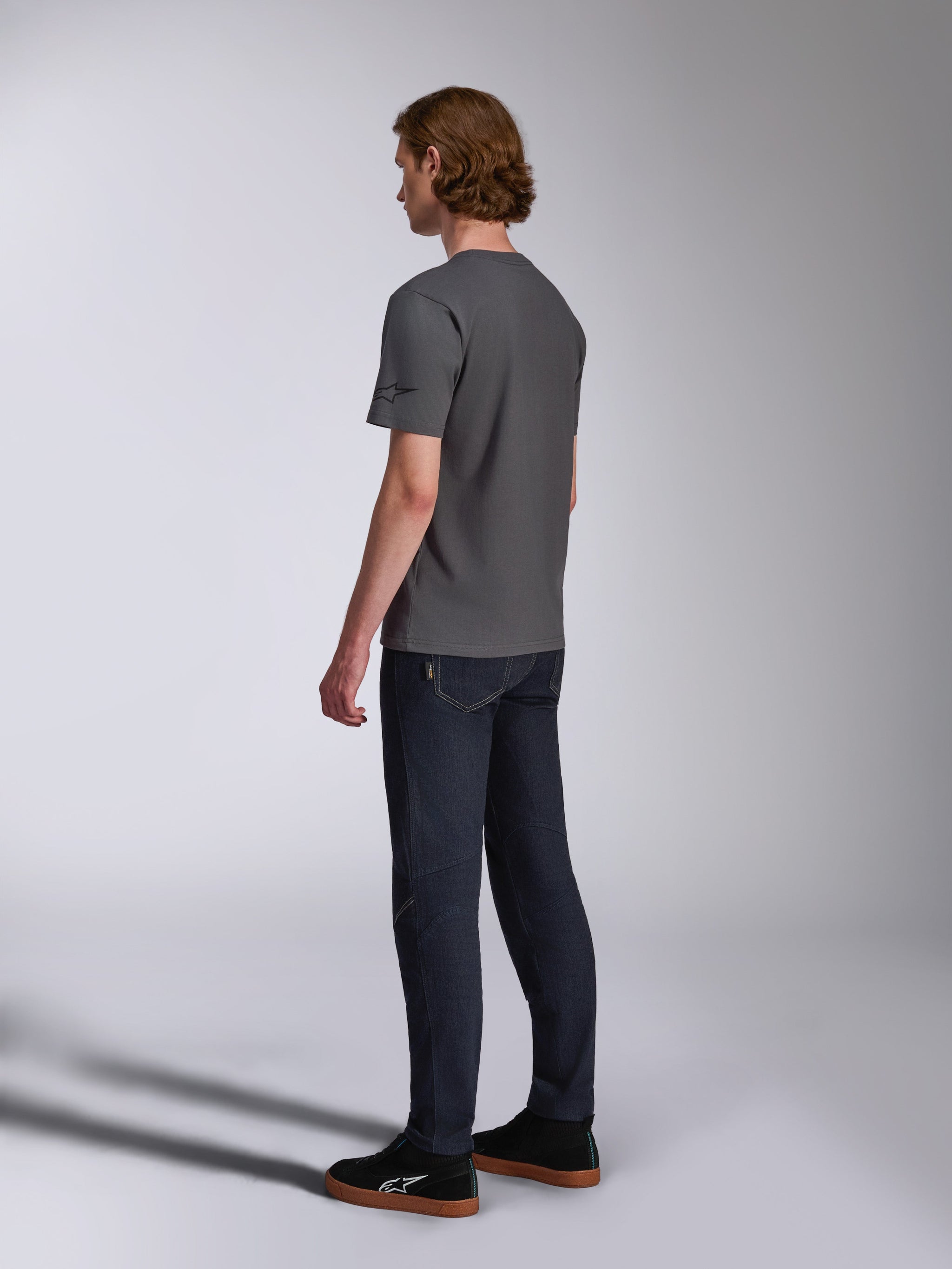 Alpinestars Waving CSF Tee, Short Sleeve T-Shirt, Charcoal, back-side view on model, small black star logo on sleeve, worn with dark denim jeans and black sneakers, casual motorsport streetwear