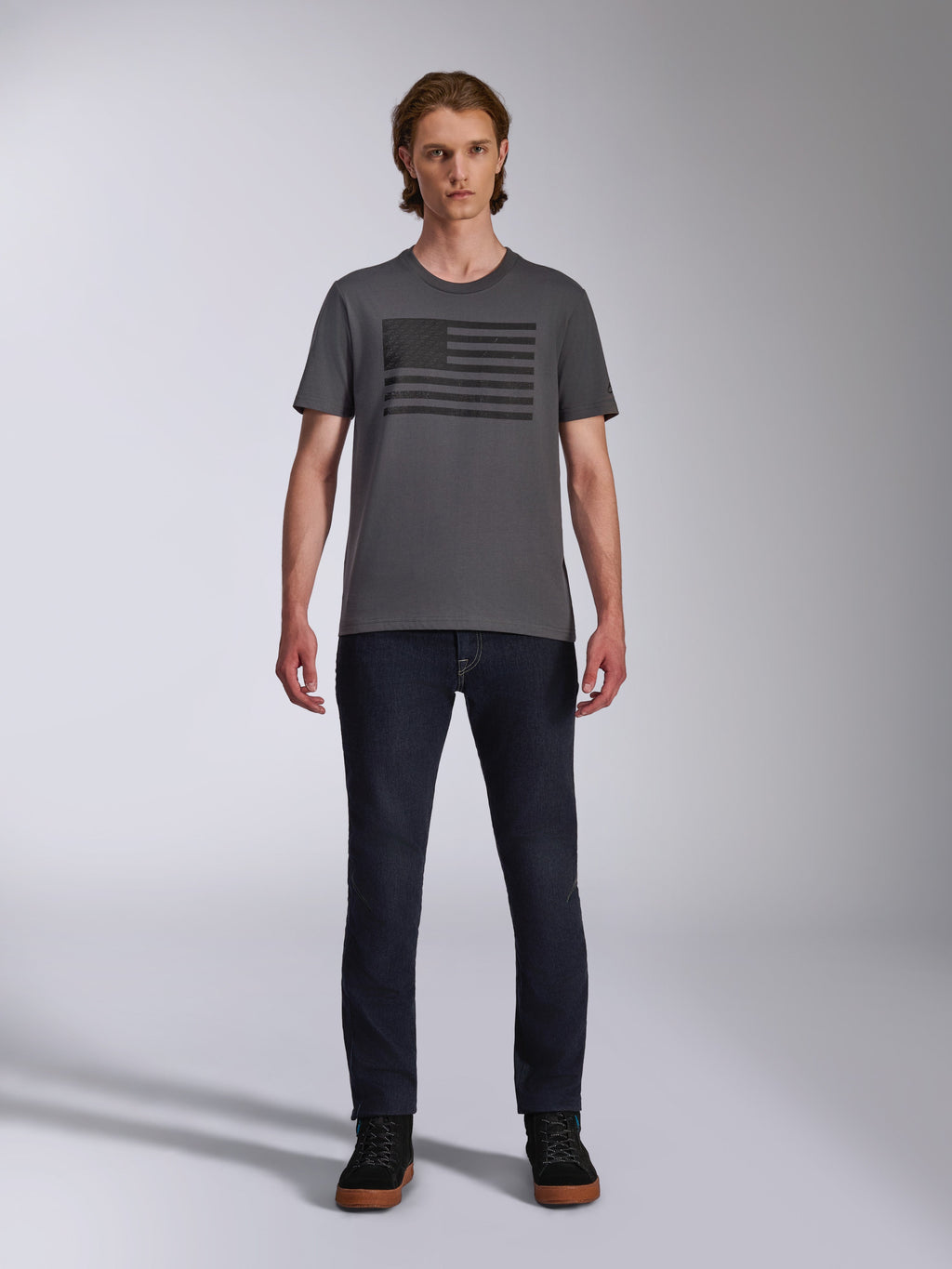 Alpinestars Waving CSF Tee, T-shirt met korte mouwen, houtskoolgrijs, zwarte Blaze 2.0 vlag-stijl logo-opdruk, casual motorsport streetwear, gedragen met donkere denim jeans