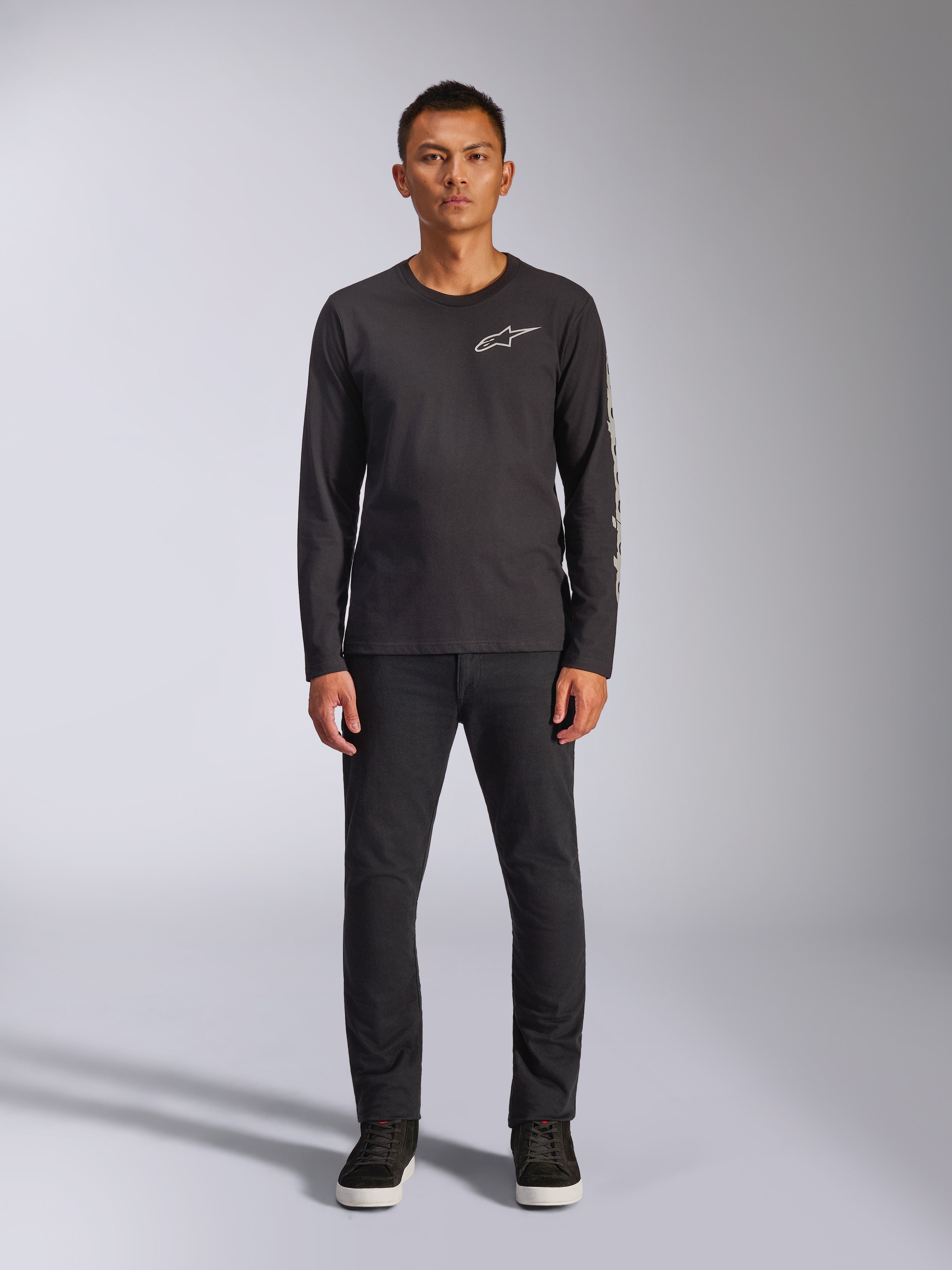 Alpinestars Trackside CSF Tee, Long Sleeve T-Shirt, Black, White Alpinestars logo on the chest and graphic branding on the sleeve, worn with black pants and sneakers, casual motorsport-inspired streetwear