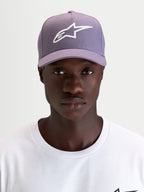 Alpinestars Ageless Snapback Pet, sportswear pet met gebogen klep, stoffen constructie in stoffig paars en wit, gedragen door een model met het geborduurde 3D Astars-logo op de voorkant